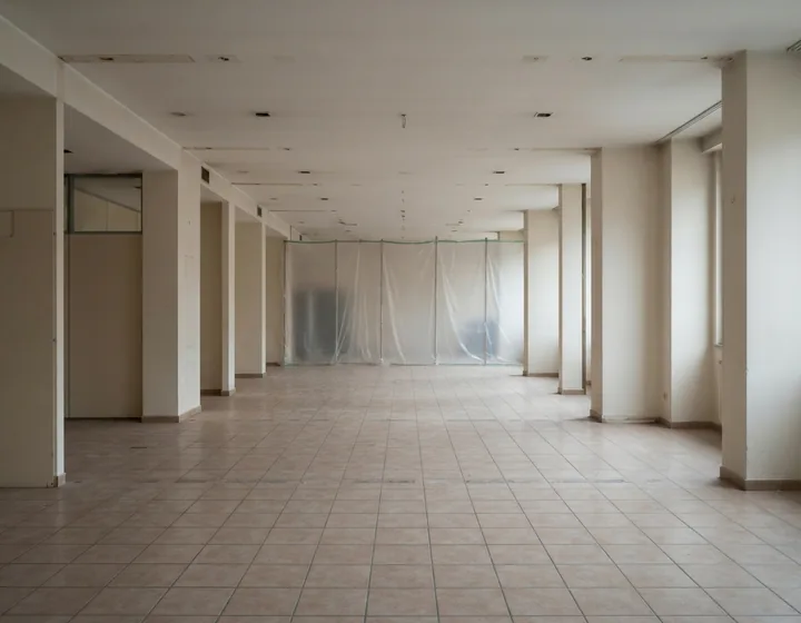 Leergeräumter Innenraum im Rückbau mit Staubschutzwand